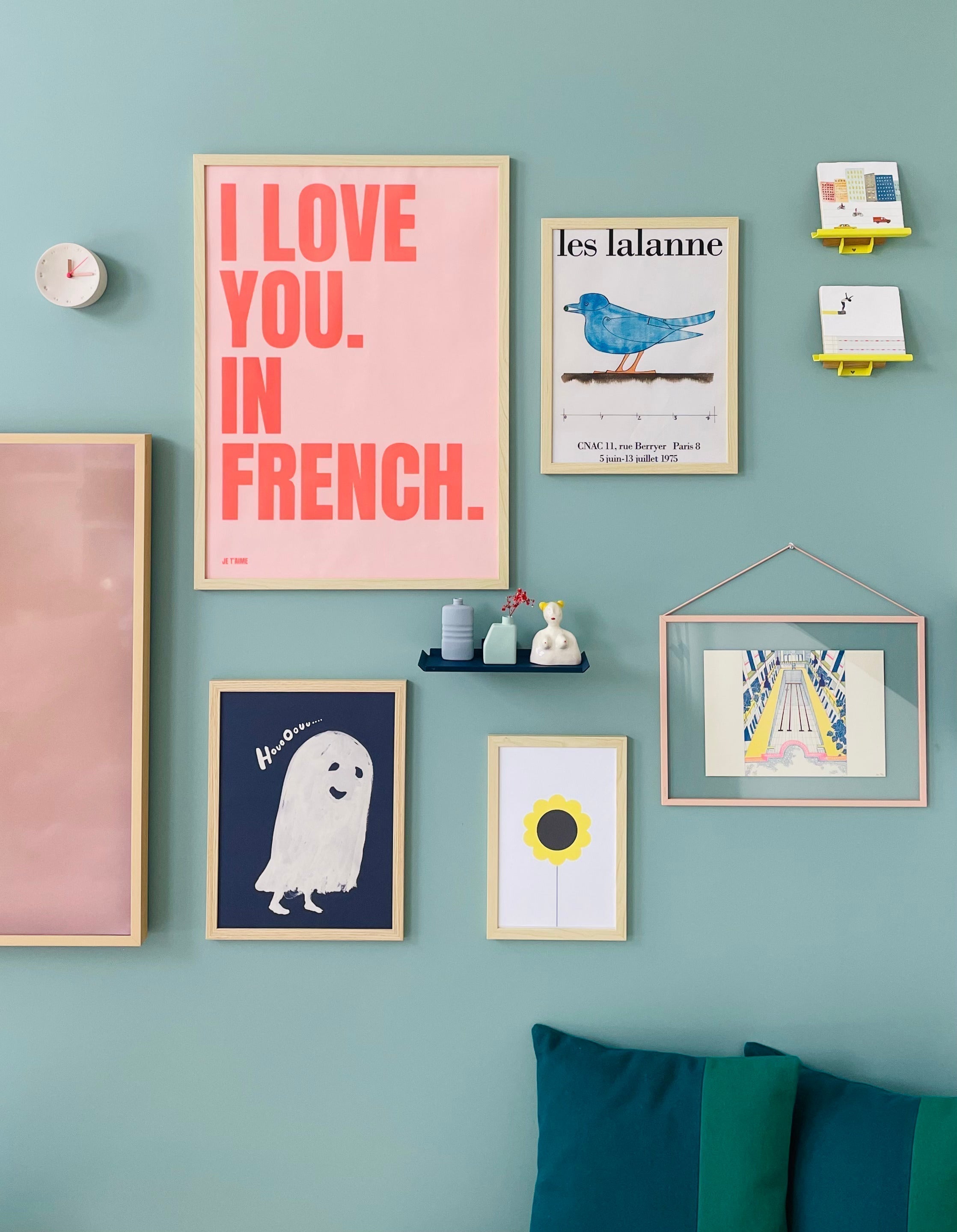 Blauw groene achterwand met kleurrijke posters en gele en blauwe wandplankjes van Mippe met daarop StoryTiles en vaasjes